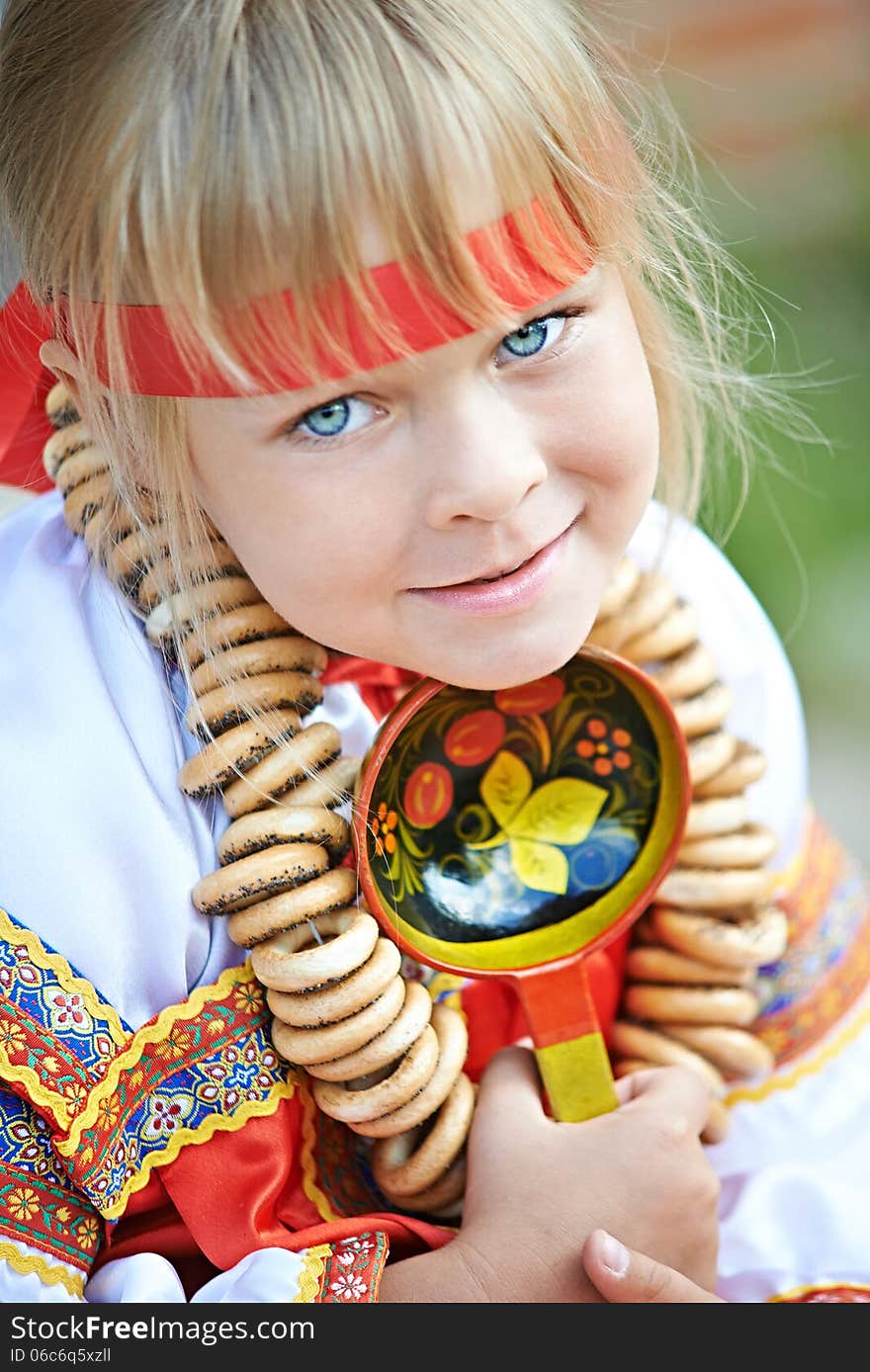 Russian girl in national costume with a spoon and bagels. Russian girl in national costume with a spoon and bagels