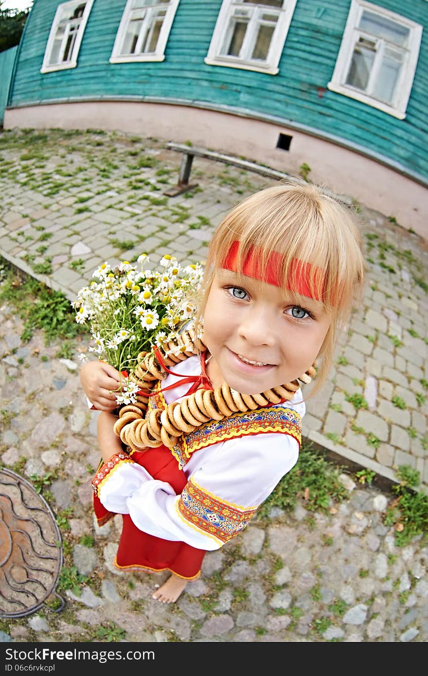 Russian girl in national costume with bagels and flowers on village