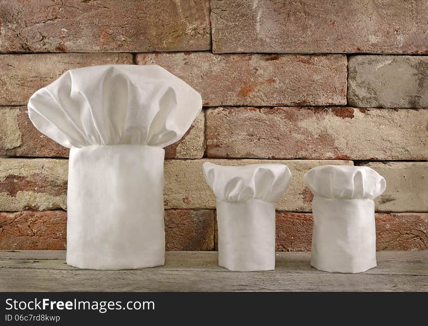 Three white toques on brick wall background. Three white toques on brick wall background