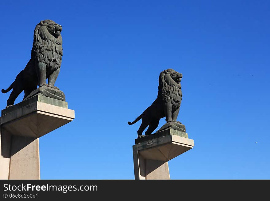 Pair of black metal lions sculpture against blue sky, Zaragoza, Spain