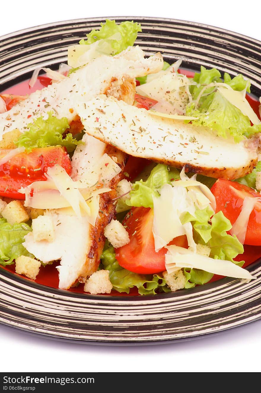 Traditional Caesar Salad with Grilled Chicken Breast, Garlic Crouton, Lettuce, Tomatoes and Grated Parmesan Cheese on Striped Plate closeup on white background