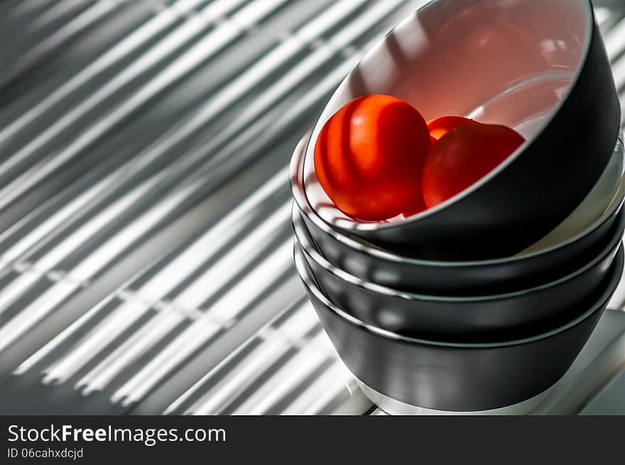 Plates stacked on the table in the band with three tomatoes. Plates stacked on the table in the band with three tomatoes