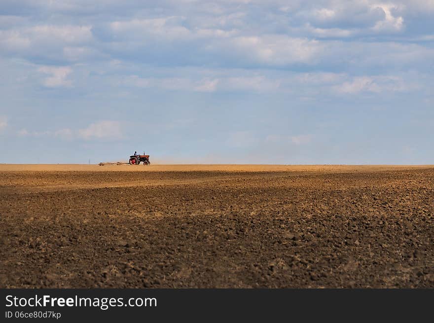 Tractor working in the field betwen between sky and ground