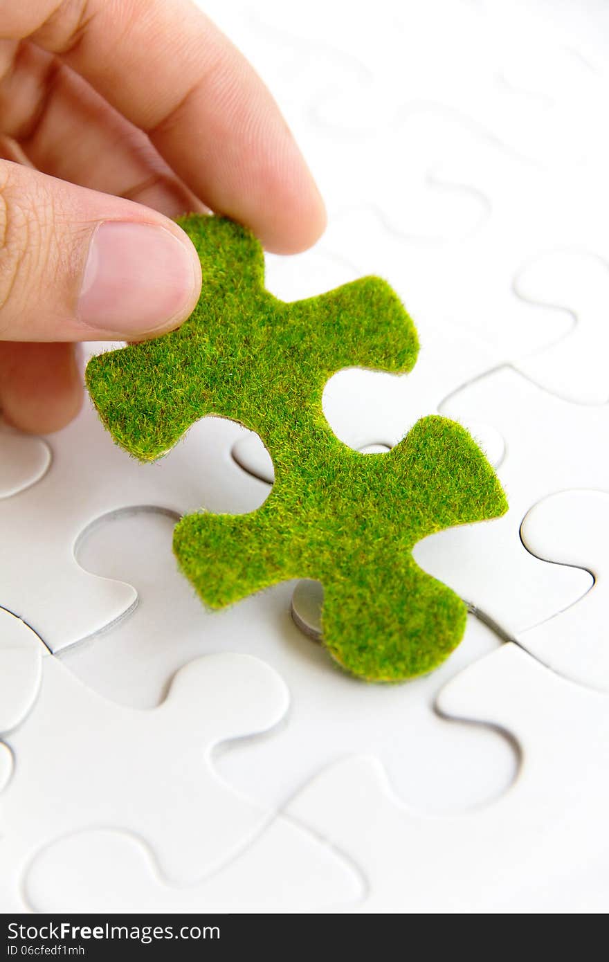 Hand Holding A Green Puzzle Piece