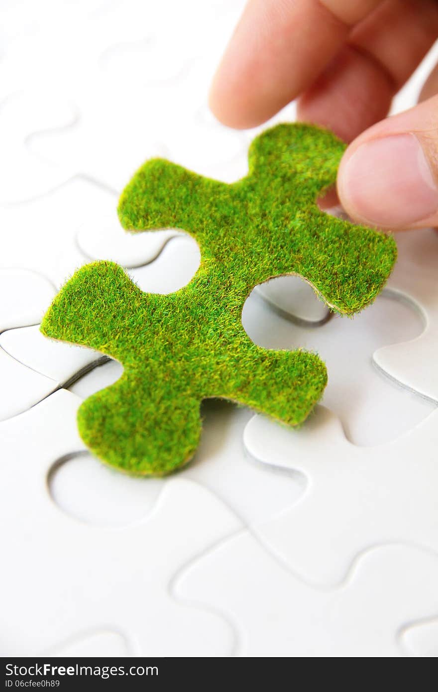 Hand holding a green puzzle piece