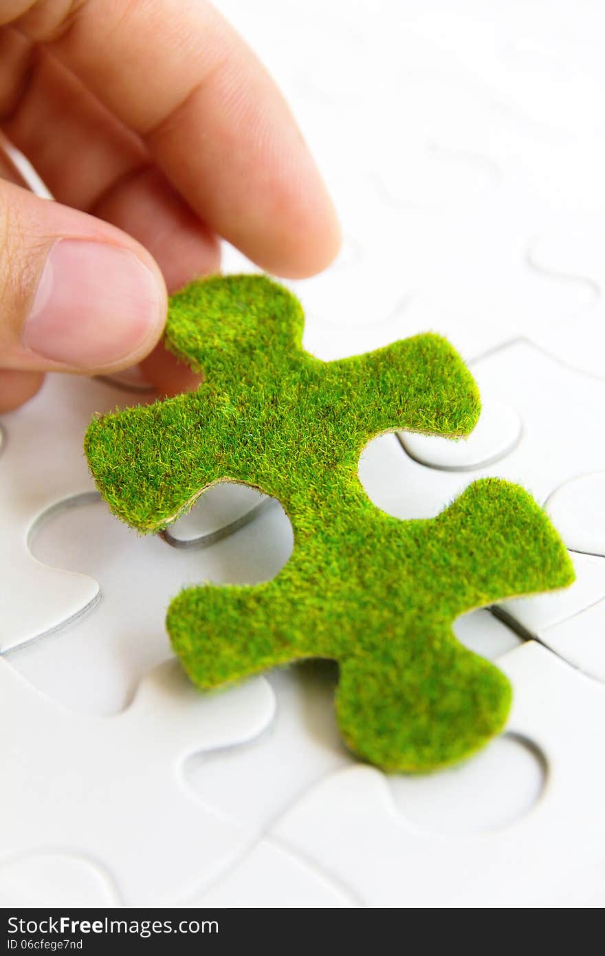 Hand holding a green puzzle piece