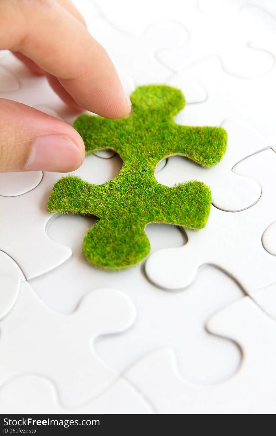 Hand holding a green puzzle piece