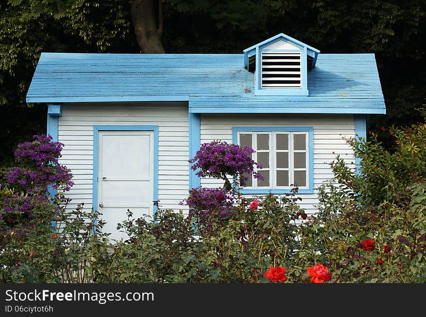 Wooden cabin among trees and flowers.