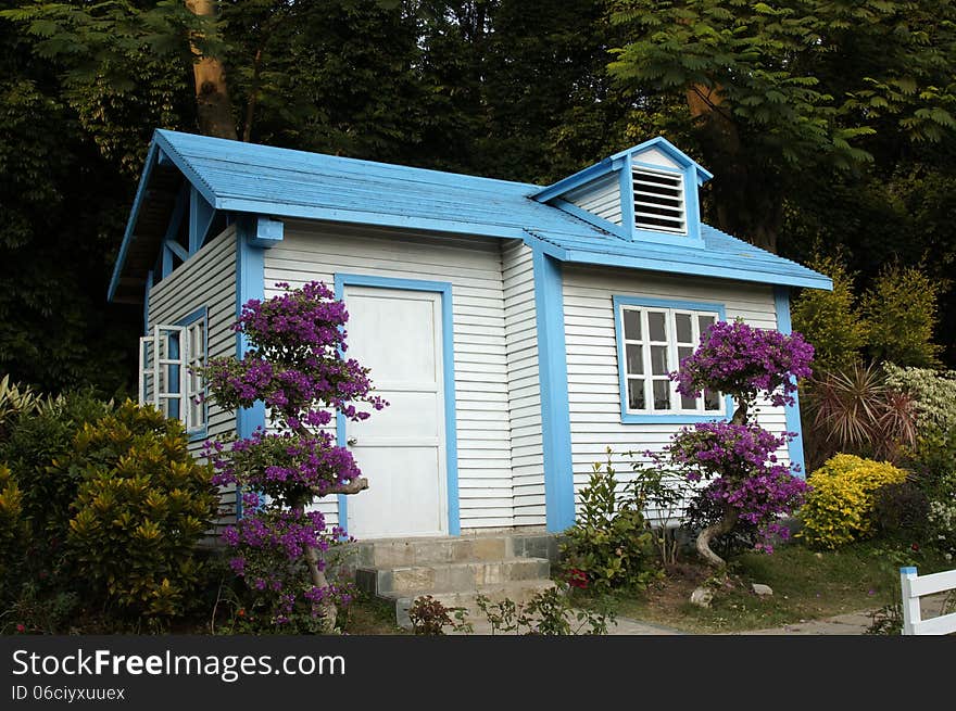 Wooden cabin among trees and flowers.