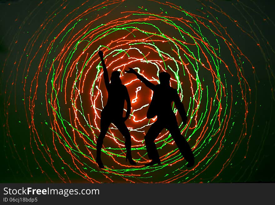 Silhouettes of a disco dancers on a modern disco background generated from laser light