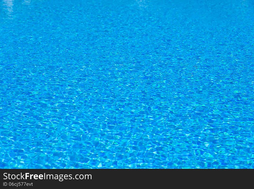 Background of blue water in the pool with the reflection of the sun