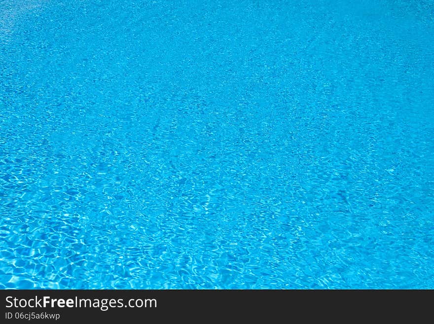 Background of blue water in the pool with the reflection of the sun