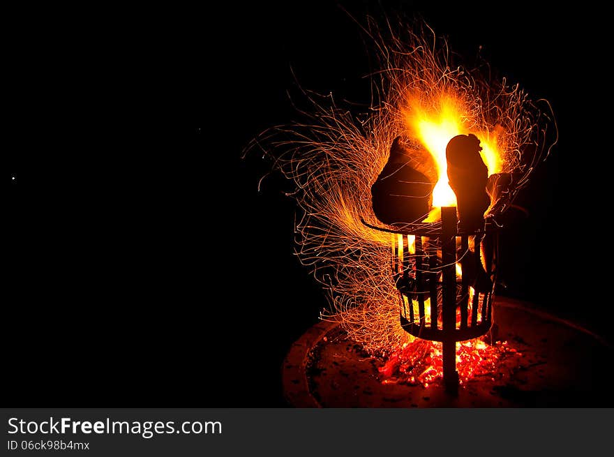 Golden yellow sparks swirl and curl around a burning campfire at night in South Africa. Golden yellow sparks swirl and curl around a burning campfire at night in South Africa.