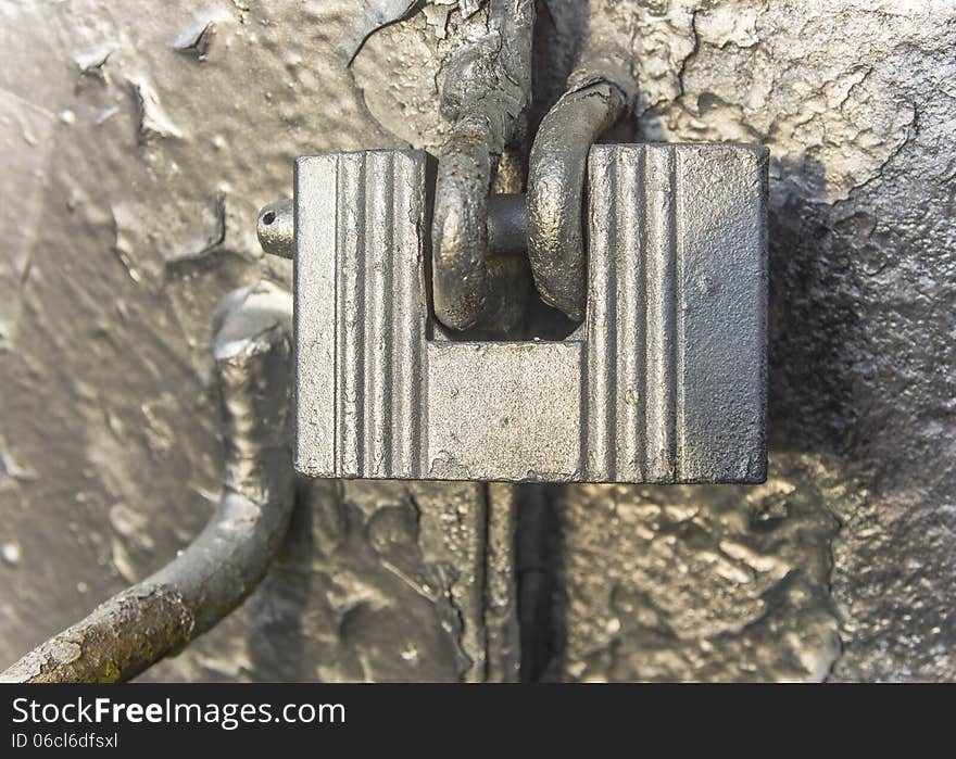 Old padlock on the metal gate in silver.