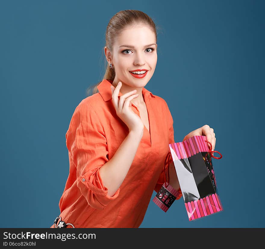 Girl in an orange shirt and jeans with shopping bag on a blue ba