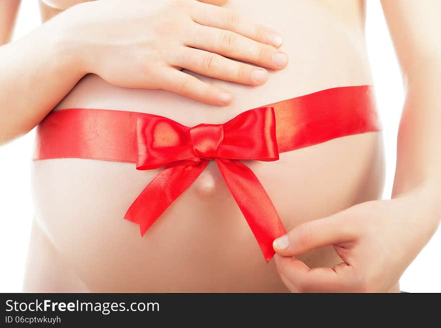 Belly of pregnant woman with red ribbon and bow