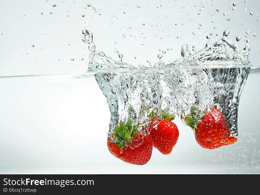 Fresh strawberry falling into the water making splash. Fresh strawberry falling into the water making splash