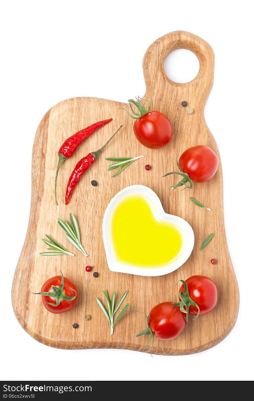 Cherry tomatoes, chili peppers, olive oil and spices on a wooden board isolated on white