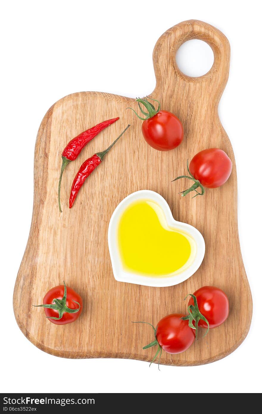 Cherry tomatoes, chilli and olive oil on wooden board, isolated