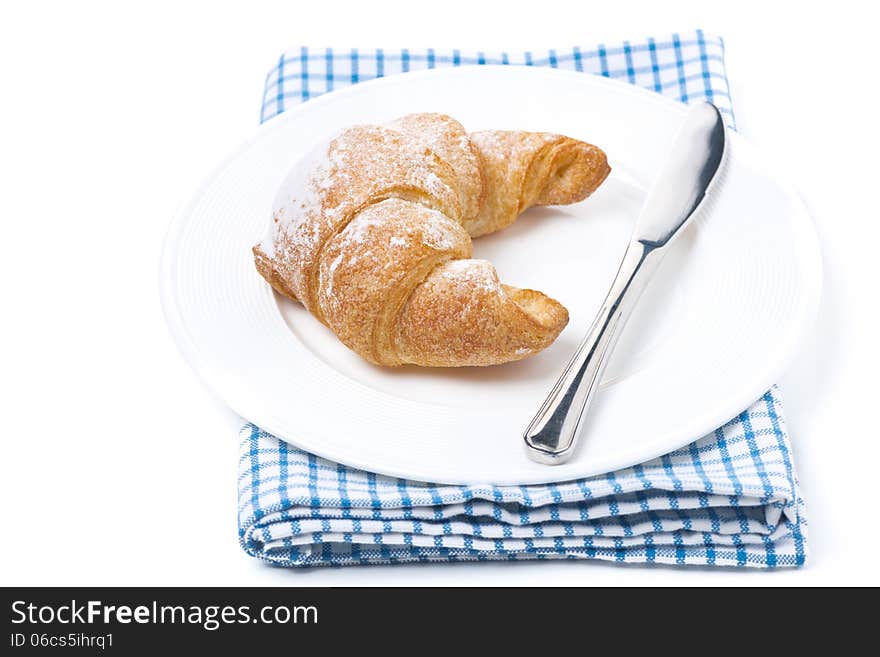 Fresh croissant and a knife on a plate isolated on white