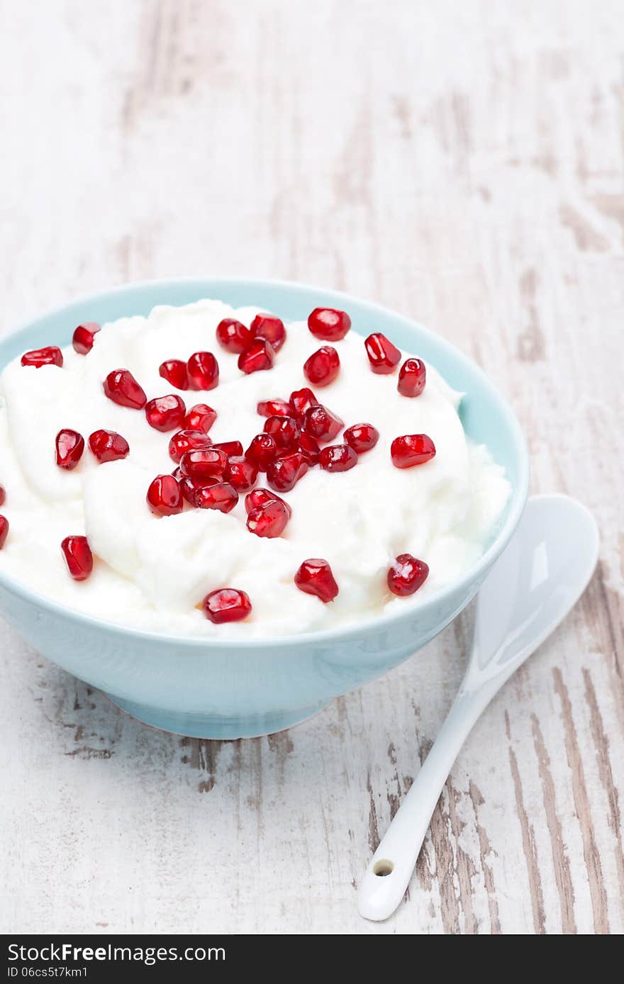 Homemade yogurt with pomegranate seeds, vertical, close-up