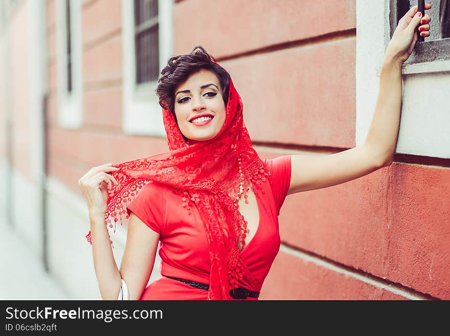 Portrait of a pretty woman, vintage style, in urban background, wearing a red dress. Portrait of a pretty woman, vintage style, in urban background, wearing a red dress