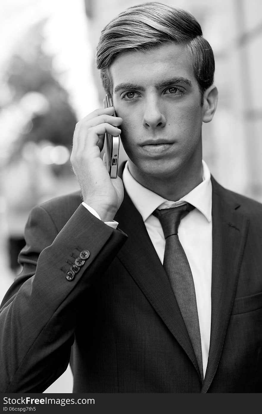 Attractive young businessman on the phone in urban background