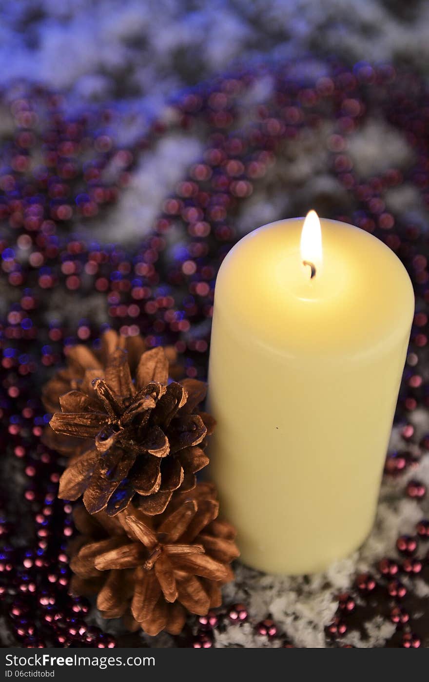 Composition of a Christmas candle, cones and beads