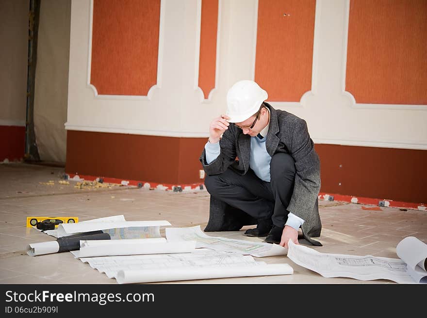 Architect or engineer in the white hard hat with the blueprint. Reconstruction interior. Architect or engineer in the white hard hat with the blueprint. Reconstruction interior.