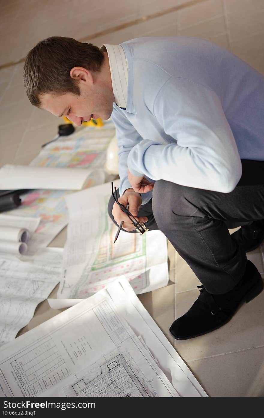 Architect looking drawings on the floor of the construction site. Architect looking drawings on the floor of the construction site.