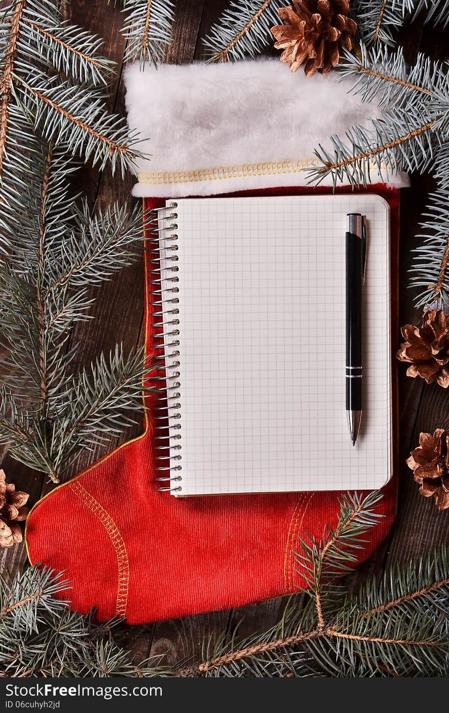 New Year`s composition of a red Christmas sock, fir branches and notebook. New Year`s composition of a red Christmas sock, fir branches and notebook