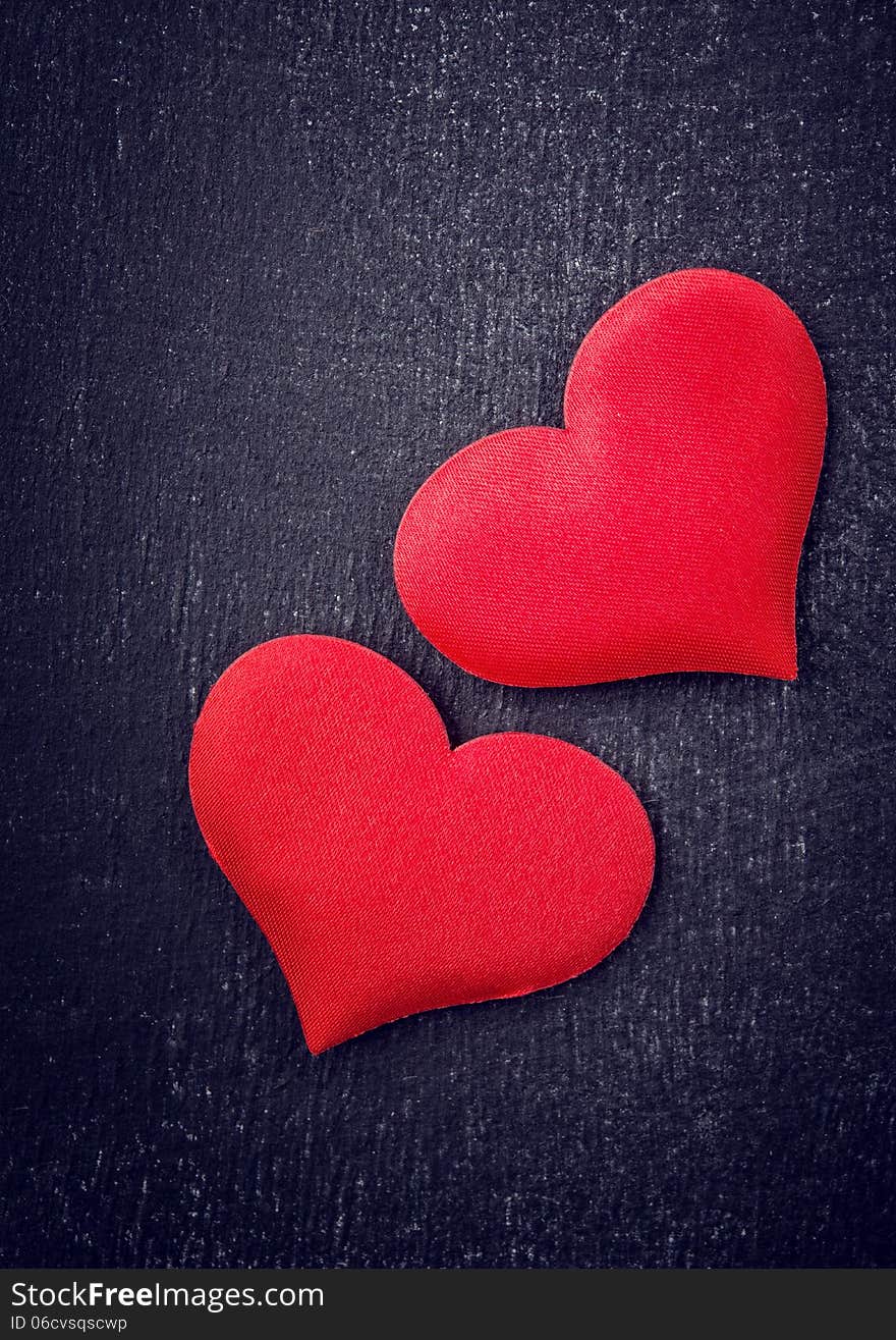 Valentine card. two red hearts on a black board