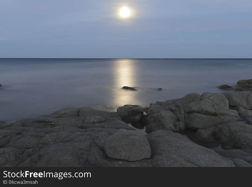 Reflections of the moon in the sea of ​​Calaliberotto, Sardinia! One of the most beautiful beach in Sardinia. Artistic view of the Moon path over the night sea with rocks and shore in the foreground. Shot with long exposure after the sunset.