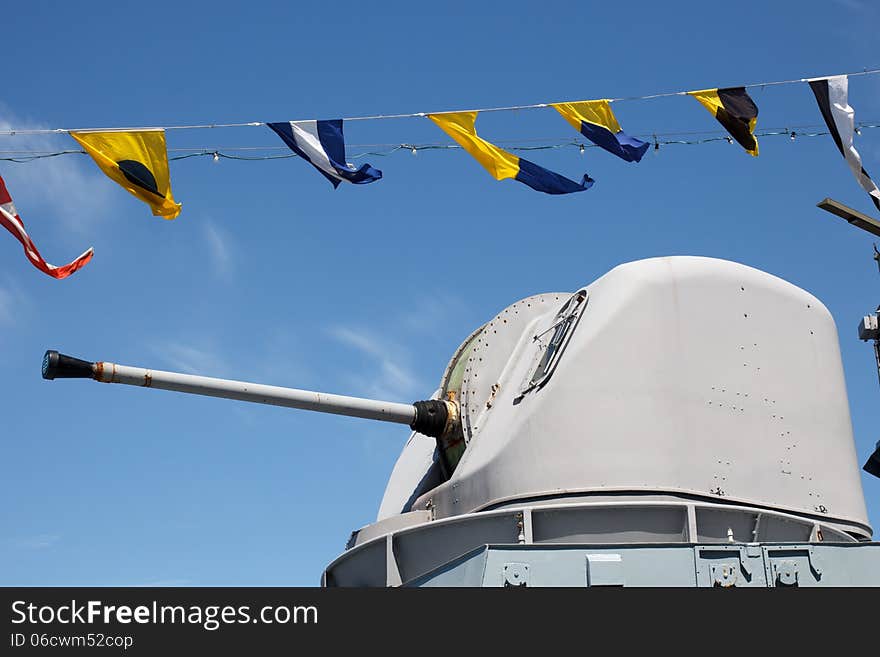 Gun on warship against blue sky