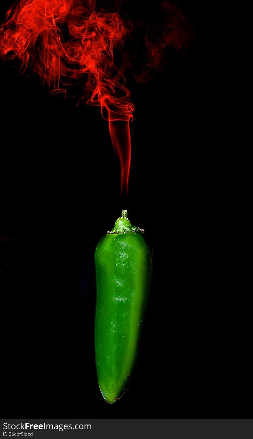 Green Chili pepper with red smoke rising from stim on black background. Green Chili pepper with red smoke rising from stim on black background