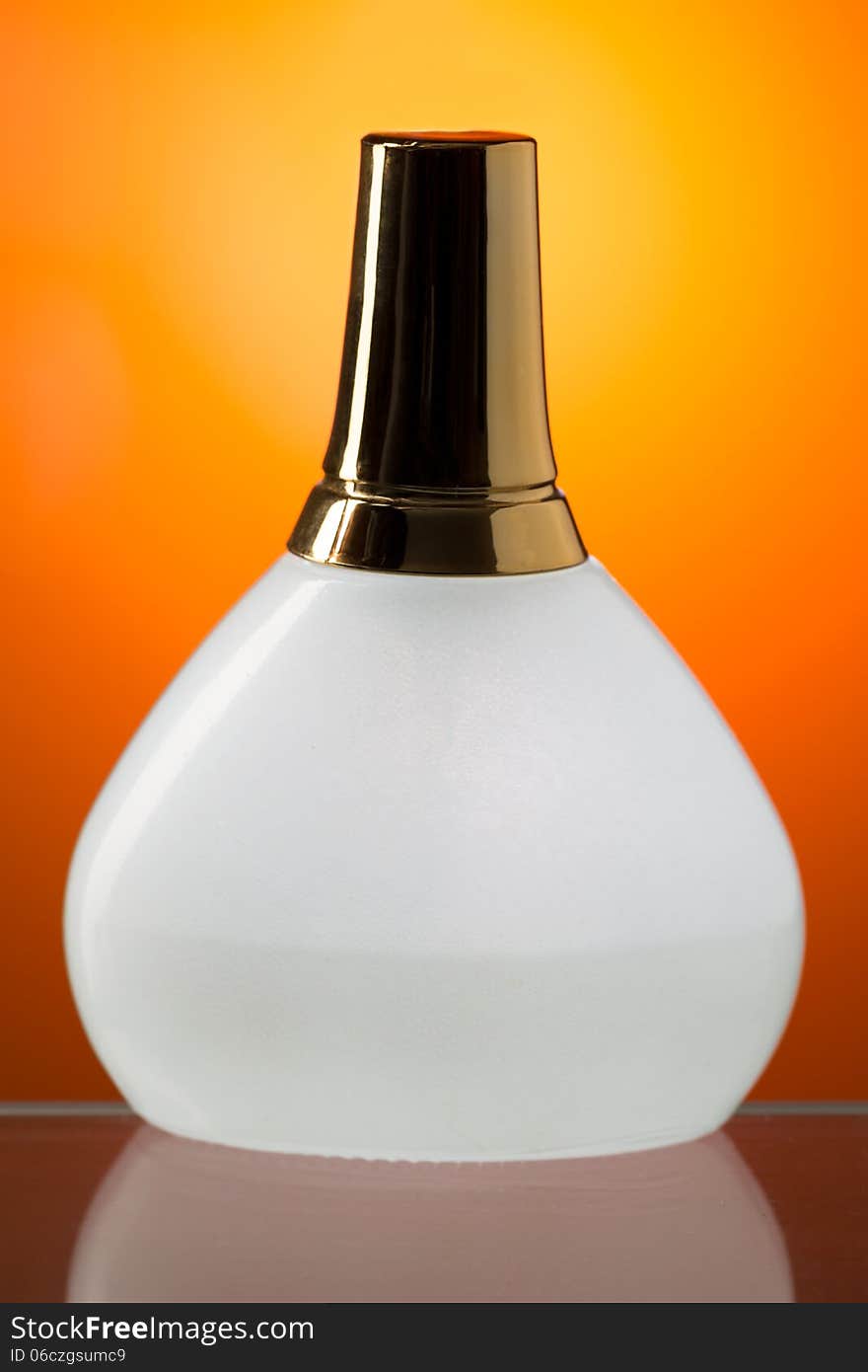 White bottle stands on the mirror surface. Orange background