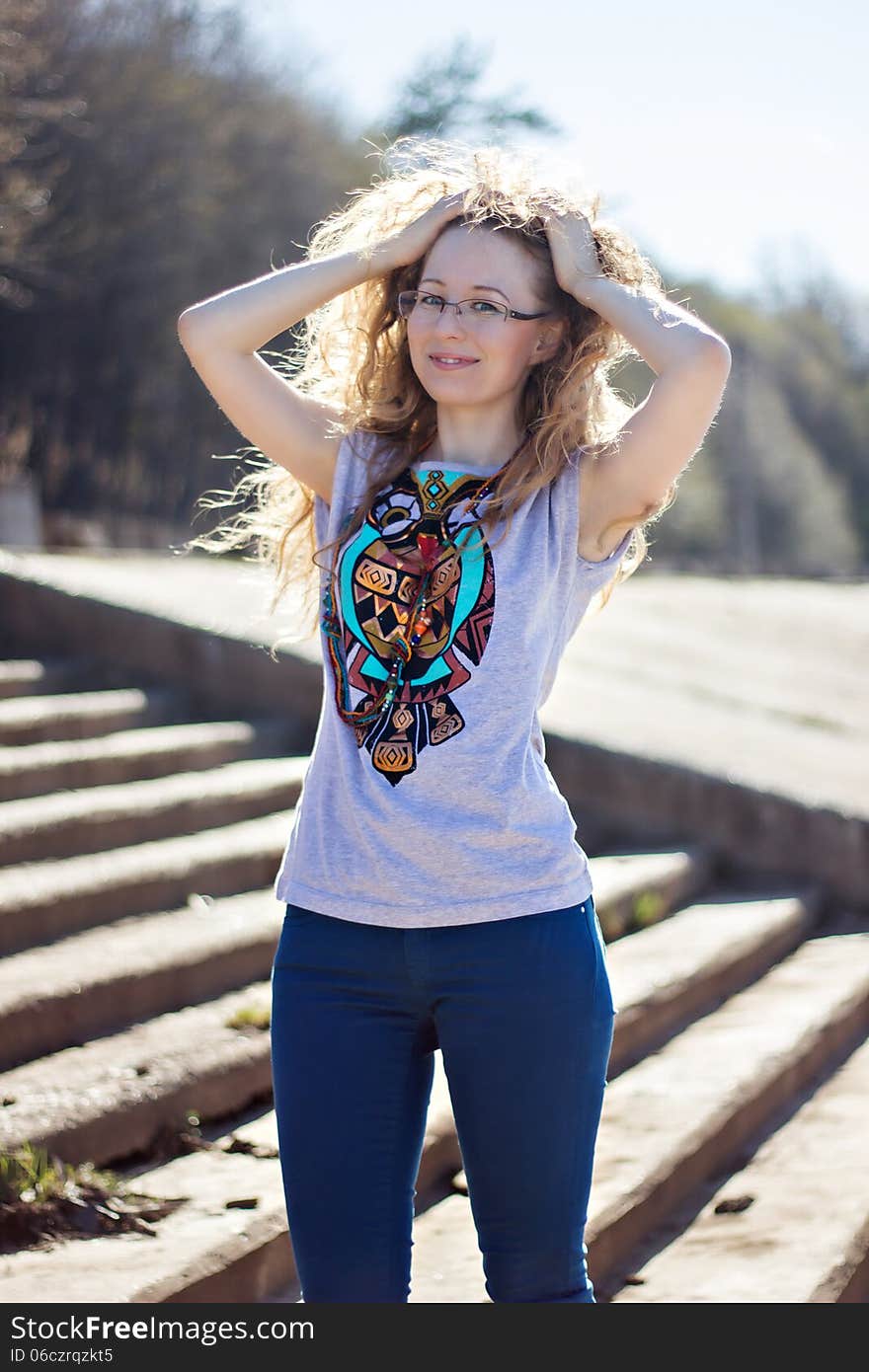 Happy woman with glasses and curly hair on bright sunny background