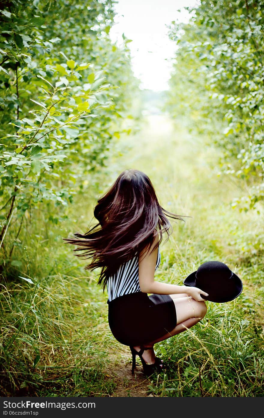 Fashionable woman waving her hair in green forest