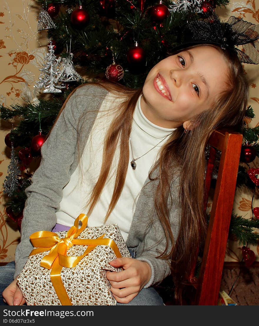 Pretty little girl in a hat sitting happy that she received a Christmas gift