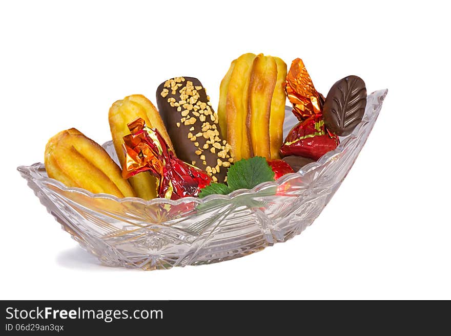 Cakes and sweets in a crystal vase on a white background