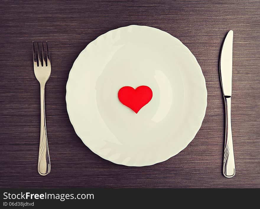 Table setting for Valentine's Day. plate, fork, knife and red heart