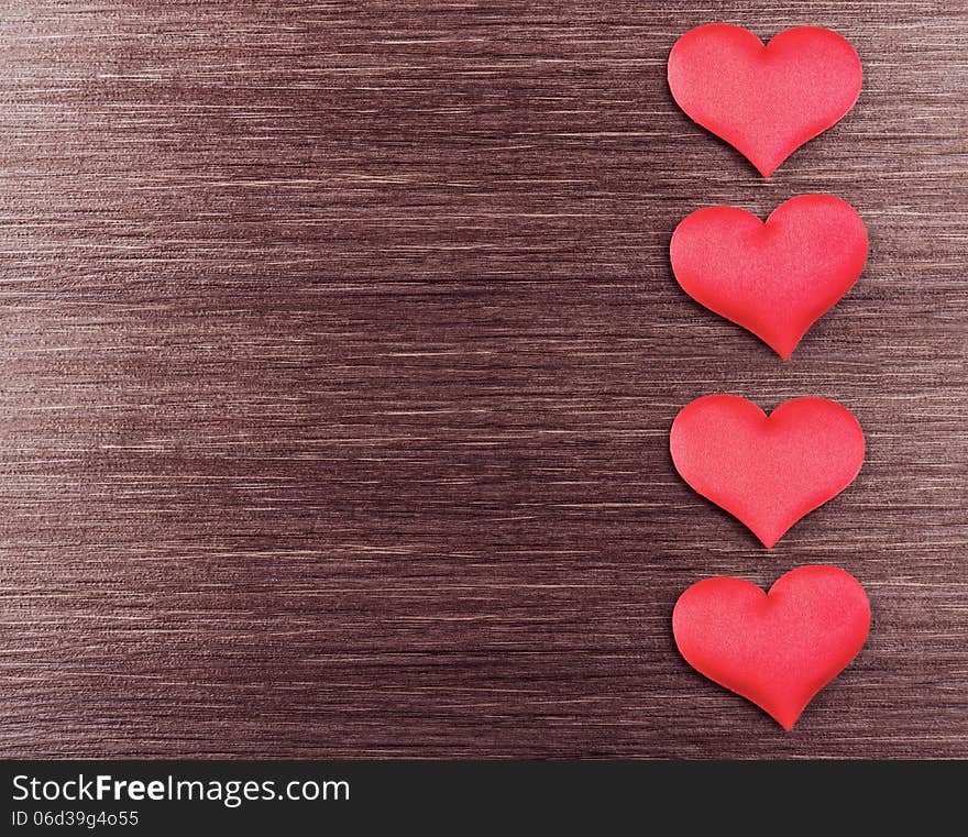 Four red hearts on a dark wooden board