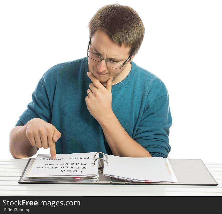 One man sitting at a desk reading paperwork with a sceptical look. One man sitting at a desk reading paperwork with a sceptical look