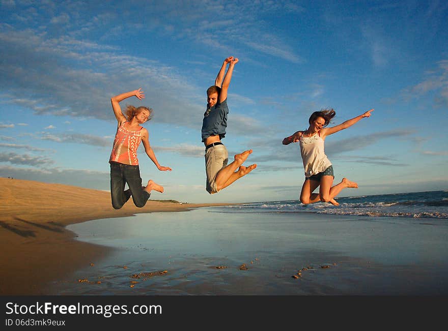 Teenagers leap high into the air at an unspoiled beach in South Africa. Teenagers leap high into the air at an unspoiled beach in South Africa.