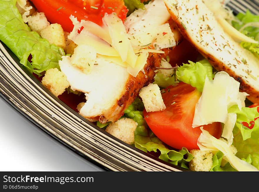 Delicious Caesar Salad with Grilled Chicken Breast, Garlic Crouton, Lettuce, Tomatoes and Grated Parmesan Cheese closeup on Striped Plate