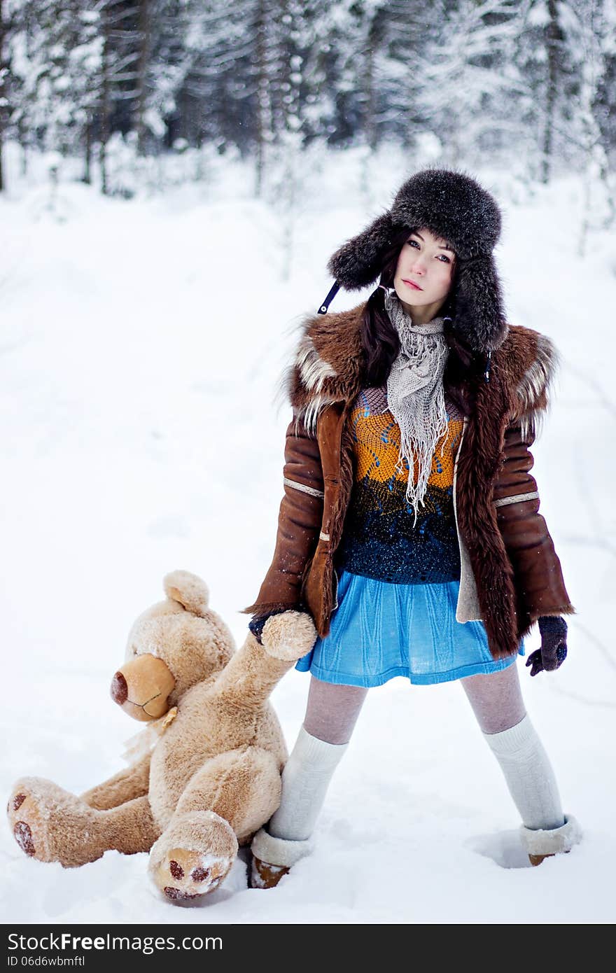 Woman in fur coat and ushanka with bear on white snow winter background