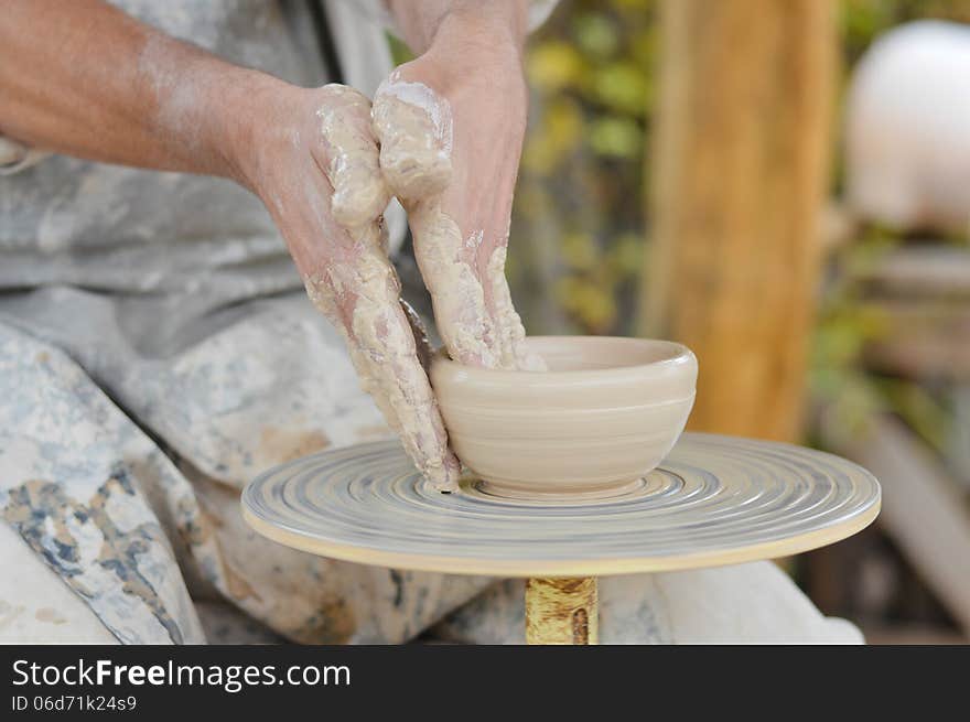 Craftsman making vase from fresh wet clay on pottery wheel