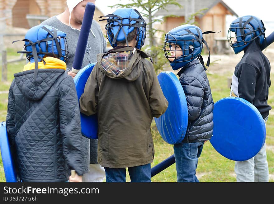 Group of school boys getting ready for fight training in rubber armor and helmets outdoors