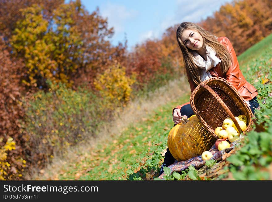 Happy beautiful young woman with basket of fresh apples