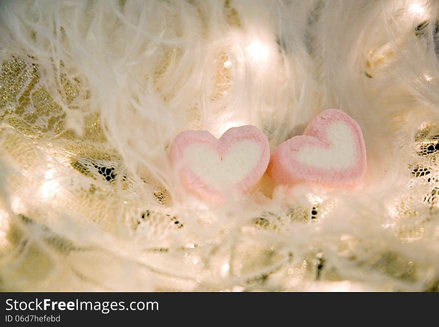 Sweet heart marshmallow on white feathers and lights